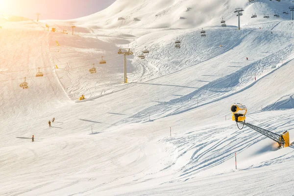 Skidlift linbana på hilghland alpina fjällvinter resort på ljusa soliga dag. panoramavidsträckt utsikt över nedförsbackar med människor njuta av sportaktiviteter. Snökanon nära pisten — Stockfoto