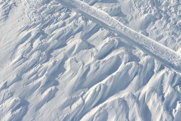 Zasněžené abstraktní terénní lyžařské zázemí s lyžařskými a snowboardovými tratěmi a tratěmi na novém panenském prašanu. ranní východ slunce nebo večerní západ slunce v horském středisku — Stock fotografie