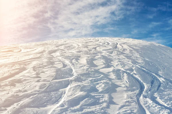 Havas elvont off-piste síelés háttér sí- és snowboard pályák és pályák új szűz por hó és kék ég a háttérben. reggeli napkelte vagy esti naplementekor alpesi hegyi dombon — Stock Fotó