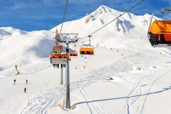 Kolejka linowa wyciągów narciarskich na wzgórzu alpejskim ośrodku zimowym w słoneczny dzień. Wyciąg krzesełkowy sposób z ludźmi cieszyć narty i snowboarding.Baner panoramiczny szeroki widok na stokach zjazdowych — Zdjęcie stockowe