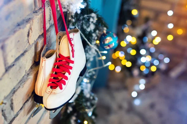 Pár fehér vintage bőr korcsolyák piros csipke lóg a régi rusztikus téglafal homályos fények karácsonyfa dekoráció. Hangulatos festői karácsonyi kártya belső téli ünnepek háttér — Stock Fotó