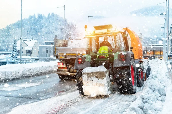 Gran tractor con cadenas en la rueda que sopla nieve de la calle de la ciudad en el cuerpo del camión de volteo con el ventilador de nieve. Limpieza de calles y remoción de nieve después de nevadas. Servicios municipales remoción de nieve en temporada de invierno — Foto de Stock