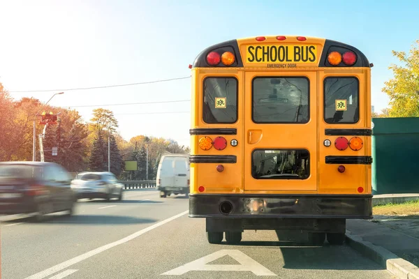 Grande clássico vintage americano ônibus escolar amarelo em pé em uma faixa de ônibus na estrada e esperando alunos e crianças para estrada de viagem escolar. Escola de ônibus de transporte porta traseira vista na rota brilhante horário da manhã — Fotografia de Stock
