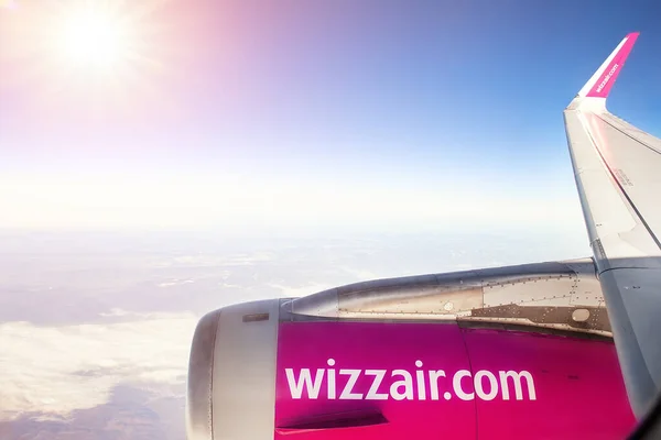 Вена, Австрия - 3 января 2020 года: Wizzair low cost economy flight company airbus plane flying over clouds with bright sun shining on background at midday. Дешевые авиабилеты и путешествия — стоковое фото