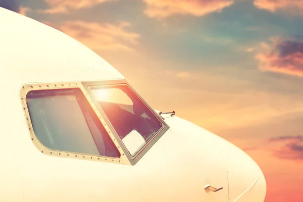 Närbild moderna passagerare kommersiella flygplan cockpit flyger mot färgglada dramatiska solnedgång himlen. Detalj sida vy av fönster i vindrutan jet kabin med lila orange blå moln på bakgrunden — Stockfoto