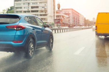 Şiddetli yağmurdan sonra otoyolda hızla ilerleyen arabalar ve arka planda sıcak gün batımı güneşi. Yağmurlu şehir caddesinde yüksek hızda giden araçlar. Su düzlemi ya da su düzlemi etkisi