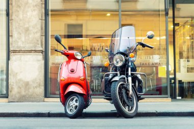 İtalyan caddesinde park edilmiş klasik kırmızı scooter ve siyah motosiklet. Çiftin sembolü, aşk, kadın ve erkeğin ilişkileri. Macera ve seyahat yaşam tarzı. İtalyan kültürü manzaralı arka plan