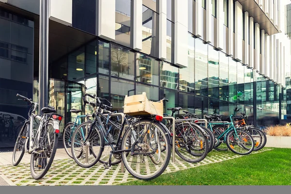 Viele Fahrräder, die in der Nähe moderner Wohnhäuser oder Hochschulcampus in der Innenstadt der europäischen Stadtstraße geparkt sind. umweltfreundlicher Transport und ein gesundes, aktives Lebensstilkonzept. Nachhaltiger Arbeitsweg — Stockfoto