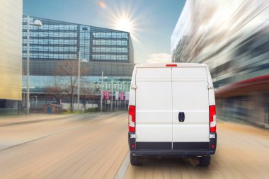 Avrupa şehir merkezine giden küçük bir kargo minibüsü. Orta kamyonlu minivan kurye aracı şehir merkezindeki bir ofis binasında paket teslim ediyor. Ticari nakliye lojistiği