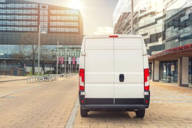 Avrupa şehir merkezine giden küçük bir kargo minibüsü. Orta kamyonlu minivan kurye aracı şehir merkezindeki bir ofis binasında paket teslim ediyor. Ticari nakliye lojistiği