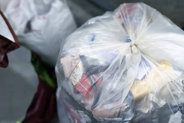 Primer plano atado bolsa de residuos de plástico doméstica llena de basura no reciclable en el punto de recogida de aceptación de reciclaje. Concepto de contaminación ambiental — Foto de Stock