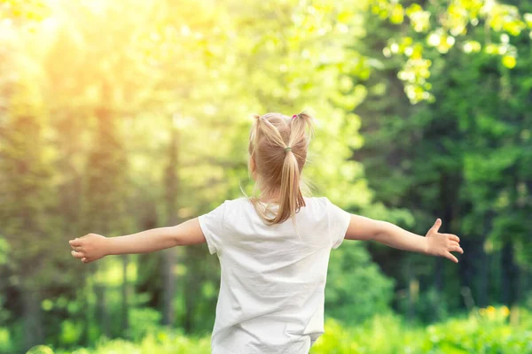 Cute uroczy mały biały dziewczynka cieszyć się stojąc w lesie podczas spaceru w letni dzień na świeżym powietrzu. Mały szczęśliwy dzieciak na kempingu przy parku przyrody. Śnij i czuj się wolny. Swobodny styl życia — Zdjęcie stockowe