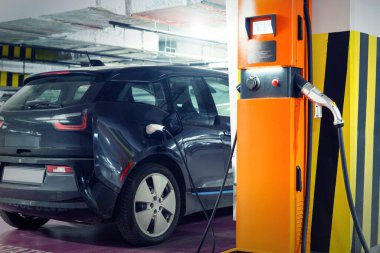 Şarj istasyonundaki elektrikli araba kapalı yer altı otoparkı bodrum katı, alışveriş merkezi ya da konut binası. Melez aracın güç kaynağı şarj bataryası. Bayilik otomat işi..