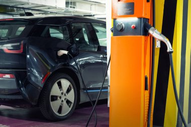 Şarj istasyonundaki elektrikli araba kapalı yer altı otoparkı bodrum katı, alışveriş merkezi ya da konut binası. Melez aracın güç kaynağı şarj bataryası. Bayilik otomat işi..