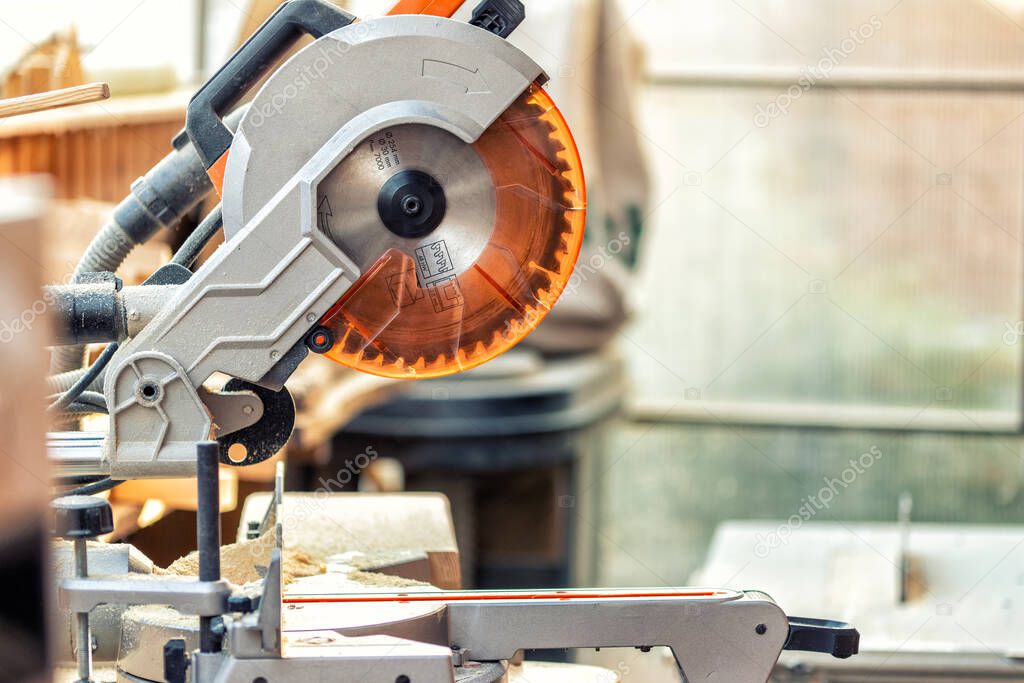 Professional compound mitre circular saw at emnty woodcraft carpentry workshop. carpenter woodworks manufacture background. Electric power tools machinery equipment. Safety covered steel jigsaw blade.