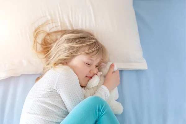 Cute adorable caucasian blond little toddler girl lying in bed on white pillow.Profile side view portrait of baby dreaming asleep at bedtime in room at home. Top view from above. Copyspace text — Stock Photo, Image