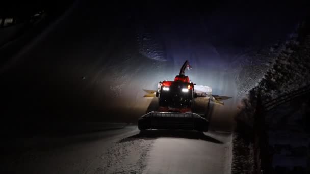 Macchina a cremagliera per gatti delle nevi che discende la pista da sci in discesa rendendo spettacolo notturno prestazioni sulla collina della pista da neve presso la stazione sciistica alpina di Ischgl in Austria. Macchinari pesanti industriali preparazione montagna — Video Stock