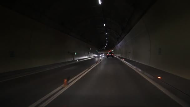 Automobilový tmavý automobilový tunel s bílými šipkami na asfaltu ukazujícím směr jízdy. Nouzový východ se spoustou světel. podzemní dopravní prostředek. Městská abstraktní městské dopravy pozadí — Stock video