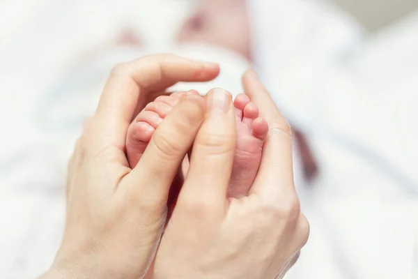 Mother making baby feet massage for newborn infant child. Mom massaging legs of small baby son.Children healthcare and happy parenthood.