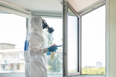 Korunaklı biyolojik giysi ve gaz maskesi takan adam koronavirüs salgını tehlikesi ve uyarısı nedeniyle. Sıhhiyeci bilim adamı hastane kliniğinde dezenfeksiyon ve havalandırma yapıyor.