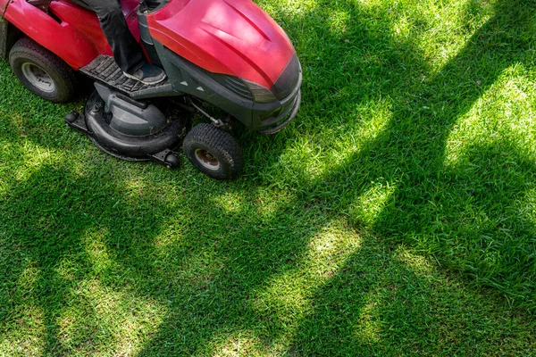 Profesyonel çim biçme makinesi işçisinin tepeden tırnağa arazi kaplama ekipman makinesiyle taze yeşil çimleri kesmesi. Bahçe ve arka bahçe çim biçme makinesi servisi ve bakımı — Stok fotoğraf