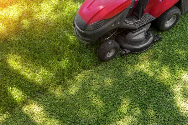 Top down above view of professional lawn mower worker cutting fresh green grass with landcaping tractor equipment machine. Garden and backyard landscape lawnmower service and maintenance.