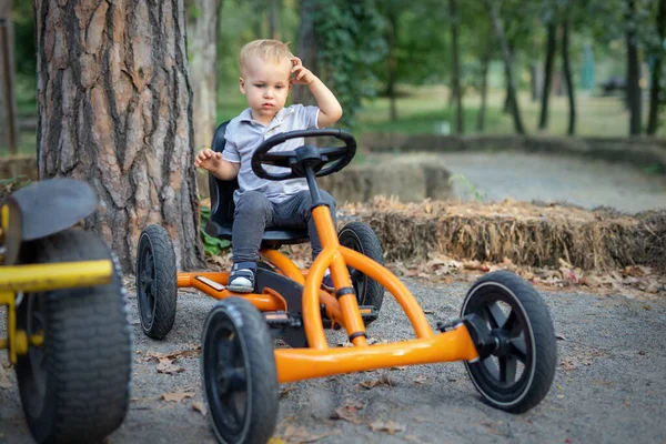 可爱的 沉思的高加索小孩坐在脚踏玩具车旁 想知道如何在公园 花园或森林里开车外出 驾驶学校课程概念 — 图库照片