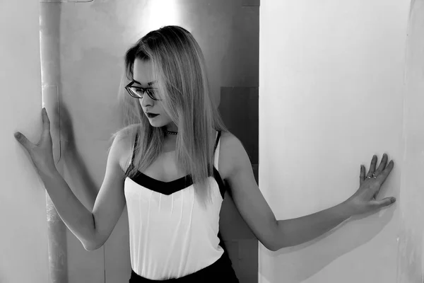 Black and white portrait of blond girl in hipster glasses, Beautiful blonde with glasses on a light background, black and white photo.