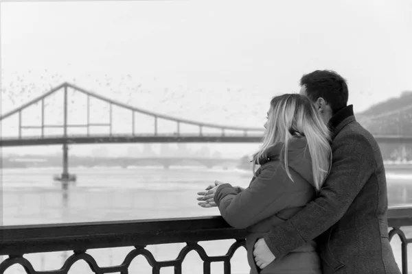 Una pareja enamorada se para en el muelle y mira hacia la distancia del río, en blanco y negro — Foto de Stock