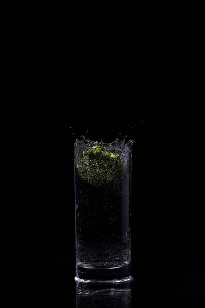 Зеленая брокколи падает в воду на белом с пузырьками воздуха Брокколи в воде, время замерзания, брызги воды — стоковое фото