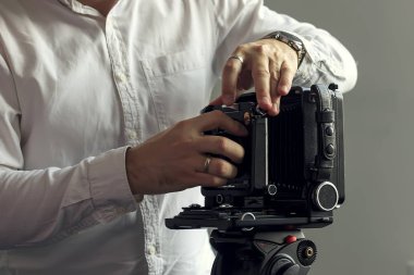 Eski kamera bir tripod üzerinde bir duvar bir arka plan üzerinde duruyor