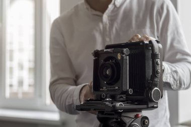 Eski kamera bir tripod üzerinde bir duvar bir arka plan üzerinde duruyor