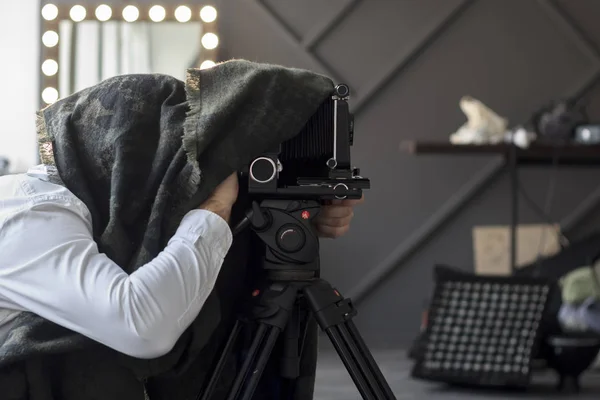 Fotograf som gömmer sig under en svart cape med retro kamera — Stockfoto