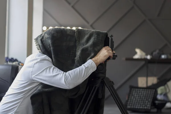 Fotograf som gömmer sig under en svart cape med retro kamera — Stockfoto