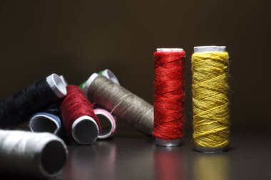 Arka plan iş parçacığı ile renkli bobinleri bir sürü ile. Bobin diğer üç satır dizilir. Sarma düzensiz. Çok renkli konu.