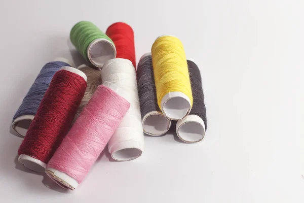 Accessori per cucire si trovano su uno sfondo bianco. Bobine multicolori di fili . — Foto Stock