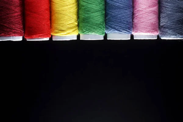 Naaien quilten draad, regenboogkleuren. op zwarte achtergrond met plaats voor uw eigen tekst — Stockfoto