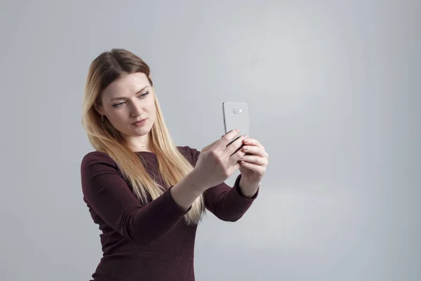 La fille fait selfie au téléphone sur un fond gris, isoler — Photo