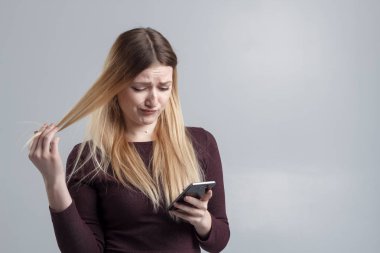 Beyaz bir arka plan üzerinde bordo elbiseli bir kız bir Sms bir rahatsız edici fan okur..