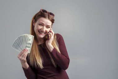 Telefonla kazanç bir iş kız görüntüsü. Güçlü bir bağımsız kadın onun elinde para ile telefonda konuşuyor.