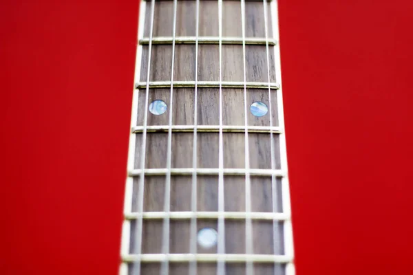 Collo di chitarra su sfondo rosso, messa a fuoco selettiva primo piano . — Foto Stock