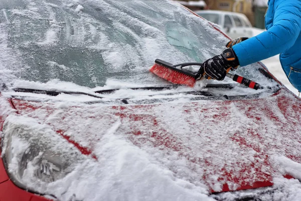 Cleaning snow. Snow-covered street. Winter landscape.Snow on cars after snowfall. Winter city scene. Cars in the snow. A man is cleaning a car after a snowstorm