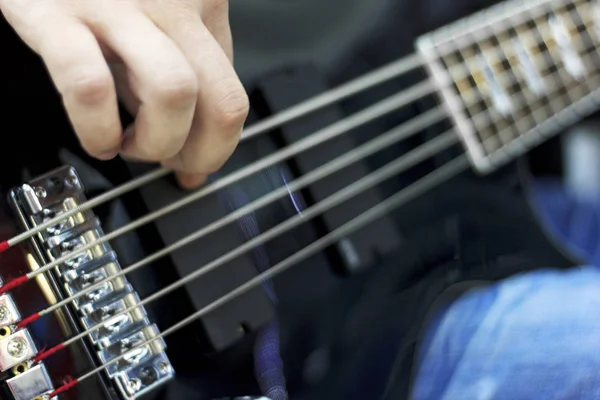 Nahaufnahme auf den Fingern eines Musikers, der auf der Bühne Bassgitarre spielt — Stockfoto