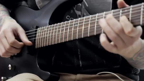 Een man met tatoeages op zijn handen spelen een elektrische gitaar in een muziekwinkel. — Stockvideo