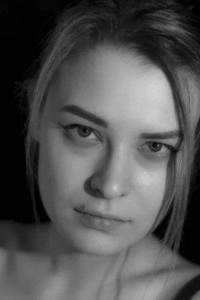 Schwarz-weiß Porträt hübsche junge Frau in Pullover auf schwarzem Hintergrund. Zurückhaltend. Innenräume. — Stockfoto