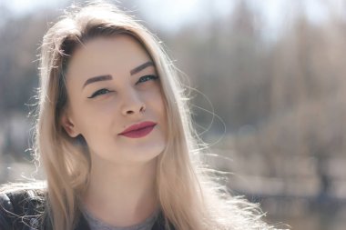 Güzel esmer bir kızın açık hava portresi. Güneşli yaz ya da bahar gününde şehrin arka planında mutlu gülümseyen bir kadın. Altın saat içinde yakın plan bir portre. Seçici odak.