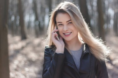 Mutlu güzel kadın parkta bir cep telefonu konuşma. Sonbahar.