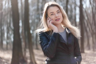 Mutlu güzel kadın parkta bir cep telefonu konuşma. Sonbahar.