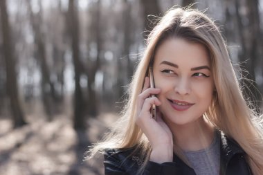 Mutlu güzel kadın parkta bir cep telefonu konuşma. Sonbahar.