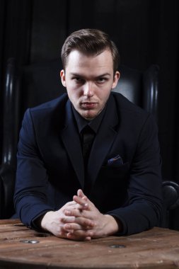 Reklam veya metin için bir yer ile pahalı bir karanlık iç arka plan üzerinde takım elbiseli bir genç adam.